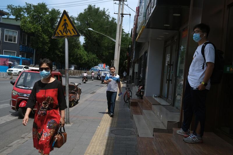 People wearing face masks are seen on a street, following a rise in cases in Beijing. Reuters