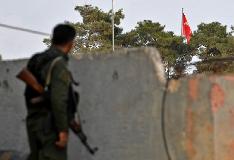 A Syrian Kurdish fighter looks at a Turkish national flag flying across the border.  AFP