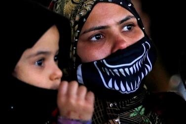 A resident of the Tahya Misr housing project in Al Asmarat district wears a face mask and carries her son in Al Mokattam, east of Cairo. Reuters