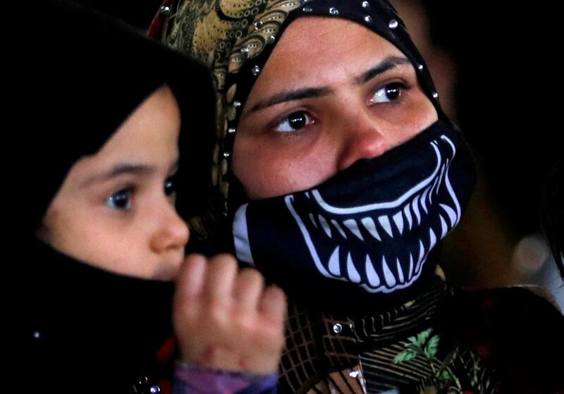 A resident of the Tahya Misr housing project in Al-Asmarat district wears a face mask and carries her son amid the coronavirus disease (COVID-19) pandemic, in Al Mokattam, east of Cairo, Egypt January 30, 2021. Picture taken January 30, 2021. REUTERS/Amr Abdallah Dalsh
