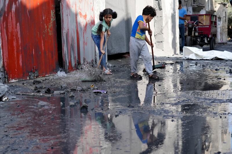 Palestinian children clean up outside their home after Israel struck Maghazi refugee camp in the Gaza Strip. AP