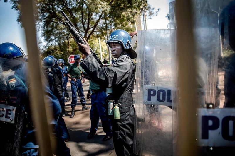 Zimbabwean anti riot police officers stand guard and close the gate of the Rainbow Towers where the election's results were announced. AFP