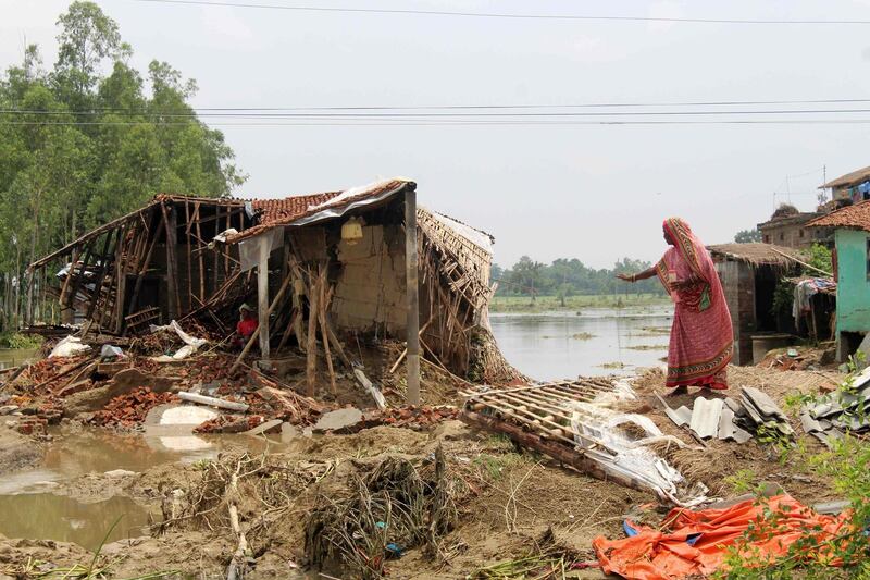 TOPSHOT - A woman stands by as a man sits in a devastated house in the Gaur district of Rautahat, some 200km south of the capital Kathmandu on July 17, 2019 as annual heavy monsoon rains flooded the area. At least 83 people have died and 17000 families have been displaced, but people have started to return as water levels recede, Home Ministry spokesman told AFP. / AFP / PHANI MAHAT
