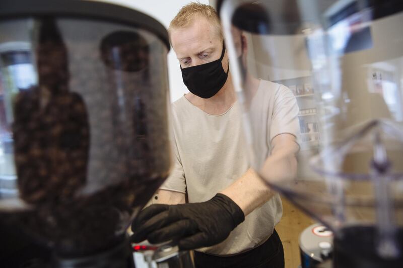 A worker wearing a protective mask grinds coffee at Breadfolks, a bakery and cafe, in Hudson, New York. Bloomberg