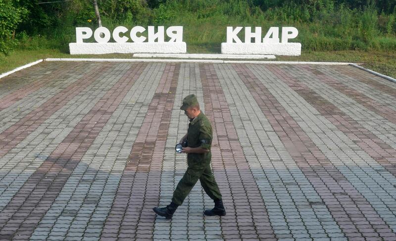 FILE PHOTO: A guard walks along a platform past signs, which read "Russia" (L) and "DPRK"(Democratic People's Republic of Korea), at the border crossing between Russia and North Korea in the settlement of Tumangan, North Korea July 18, 2014. REUTERS/Yuri Maltsev/File Photo