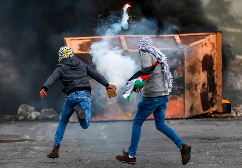 A Palestinian man throws back a tear gas canister during clashes with Israeli forces at a Land Day protest. AFP