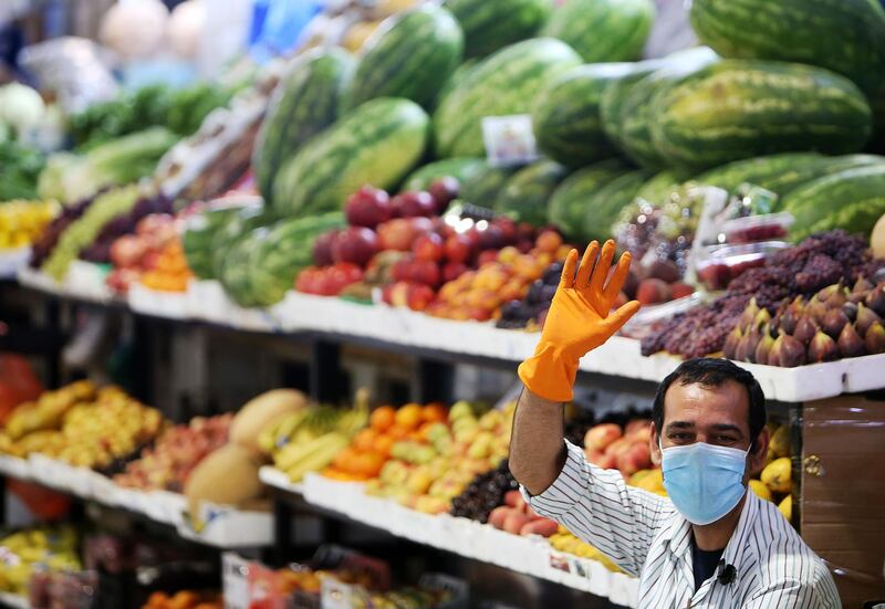 A fruit vendor wearing a face mask waves as he waits for customers in Kuwait City.  AFP