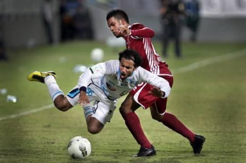 ABU DHABI, UNITED ARAB EMIRATES -  December 23, 2011 -  Adnan Hussain #66 for Bani Yas and Mahmoud Khamis #26 for Al Wahda battle for control during their match Friday night, December 23, 2011. The game ended in a tie.    ( DELORES JOHNSON / The National )