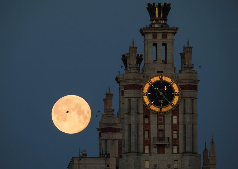 A bird flies past the full Moon as it is seen behind the Lomonosov Moscow State University in Moscow, Russia. Reuters