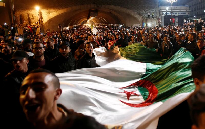 People carry a national flag as they celebrate on the streets after Mr Bouteflika submitted his resignation, in Algiers, April 2, 2019. Reuters