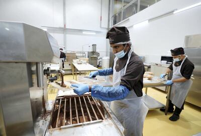 Dubai, United Arab Emirates - June 24, 2019: Chocolatiers Mumeen Abdul Wakkil (L) and Sajith Narayanan crafting hazelnut-chocolate bars. A tour round Al Nassma chocolate factory the first company to produce camel milk chocolate. Monday the 24th of June 2019. Silicone Oasis, Dubai. Chris Whiteoak / The National