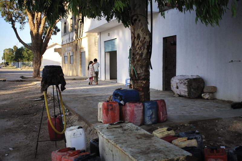 Two local children walk past a makeshift gasoline dealer at a roadside stop south of Kasserine, Tunisia near the border with Algeria. Lindsay Mackenzie for The National.