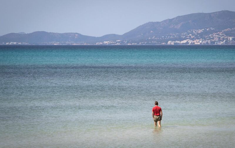 A tourist walks in the water on Palma Beach in Palma de Mallorca. AFP