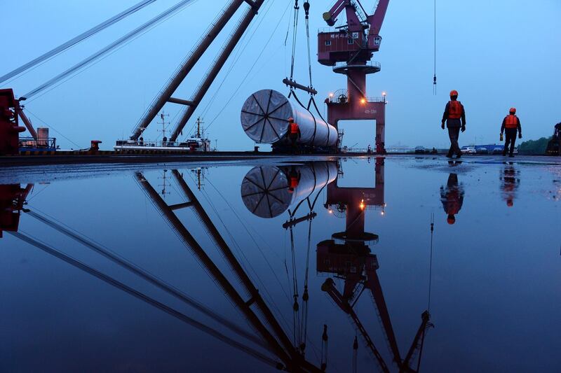 Workers are seen near a crane lifting offshore wind energy equipment by China Construction Industrial and Energy Engineering Group Co at a port in Nanjing, Jiangsu province. China Daily via Reuters
