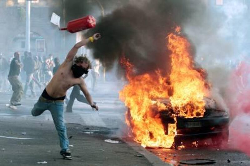 A protestor hurls a canister towards police next to a burning car during clashes in Rome, Saturday, Oct. 15, 2011. Protesters in Rome smashed shop windows and torched cars as violence broke out during a demonstration in the Italian capital, part of worldwide protests against corporate greed and austerity measures, entitled Occupy Wall Street. (AP Photo/Gregorio Borgia) *** Local Caption ***  APTOPIX Italy Wall Street Protests.JPEG-0e4bb.jpg