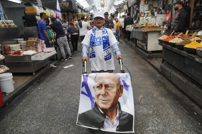 A supporter of the Likud party pushes a trolley covered with a poster bearing a portrait of Israeli Prime Minister Benjamin Netanyahu in Jerusalem. AFP