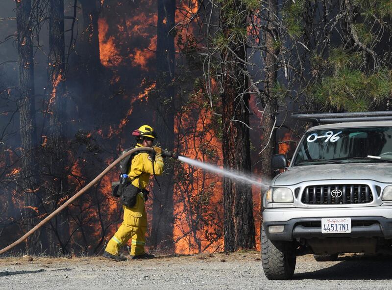 A firefighter saves a vehicle from encroaching flames as the Carr fire spreads towards the town of Douglas City near Redding, California.  AFP PHOTO / Mark RALSTON