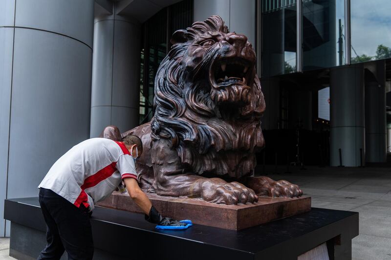 A worker cleans a statue of a lion in front of the HSBC Holdings Plc headquarters building in Hong Kong. Bloomberg