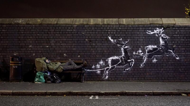 A man lays on a bench next to a new mural by Banksy in Birmingham, Britain, December 9, 2019, in this picture obtained from social media. @banksy/Instagram via REUTERS THIS IMAGE HAS BEEN SUPPLIED BY A THIRD PARTY. MANDATORY CREDIT. NO RESALES. NO ARCHIVES.