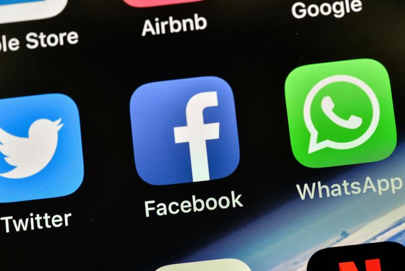 FILE - In this Nov. 15, 2018, file photo the icons of Facebook and WhatsApp are pictured on an iPhone in Gelsenkirchen, Germany. Facebook is already the leader in enabling you to share photos, videos and links. It now wants to be a force in messaging, commerce, payments and just about everything else you do online. (AP Photo/Martin Meissner, File)