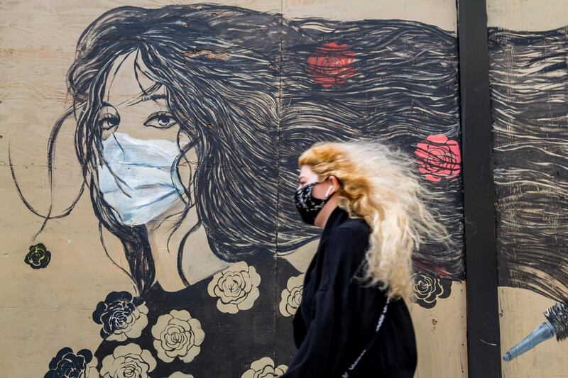 A pedestrian wearing a protective mask walks past a mural in San Francisco, California. Bloomberg