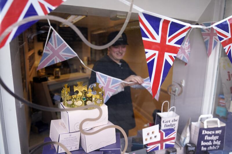 A member of staff at Fudge Kitchen puts up bunting in Windsor. PA