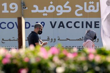 A man and a woman walk past a health ministry sign about vaccination outside a medical centre in Dubai on February 16. AFP / Karim SAHIB