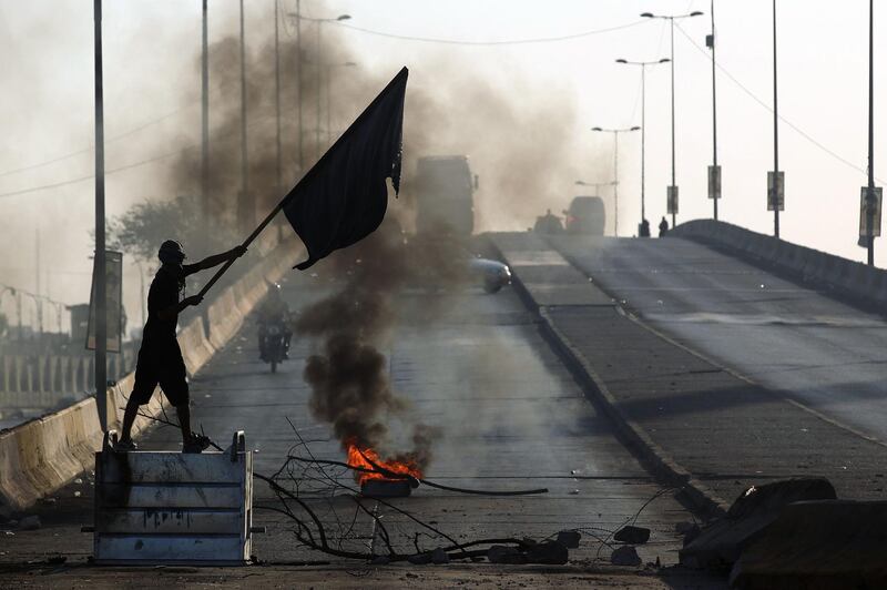 An Iraqi demonstrator waves a flag as he stands on top of a trash bin during a demonstration against state corruption, failing public services, and unemployment, in the Iraqi capital Baghdad. AFP