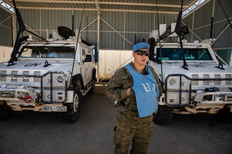 A soldier stands in front of UN-marked vehicles 