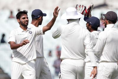 India's Bhuvneshwar Kumar, left, celebrates with teammates the dismissal of Sri Lanka's Dimuth Karunaratne during the third day of their first test cricket match in Kolkata, India, Saturday, Nov. 18, 2017. (AP Photo/Bikas Das)