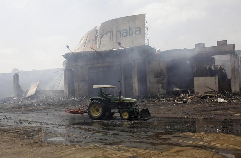A tractor runs past a damaged building on the tarmac. Athar Hussain/Reuters