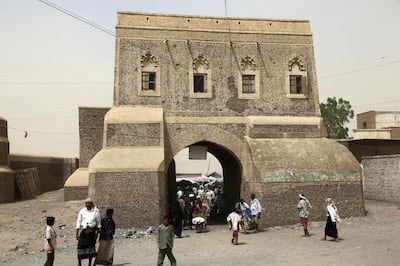 A picture taken on February 24, 2018 shows Yemenis walking through a gateway into a market in the ancient city of Zabid, a UNESCO World Heritage Site currently on the list of World Heritage in danger, in the western Hodeidah province. (Photo by ABDO HYDER / AFP)