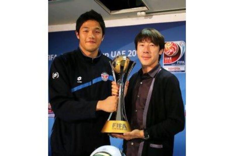 Shin Tae-yong, right, the Seongnam Ilhwa Chunma coach, and his goalkeeper, Juny Sung-ryong, hold the Club World Cup trophy during a press conference in Abu Dhabi last night.