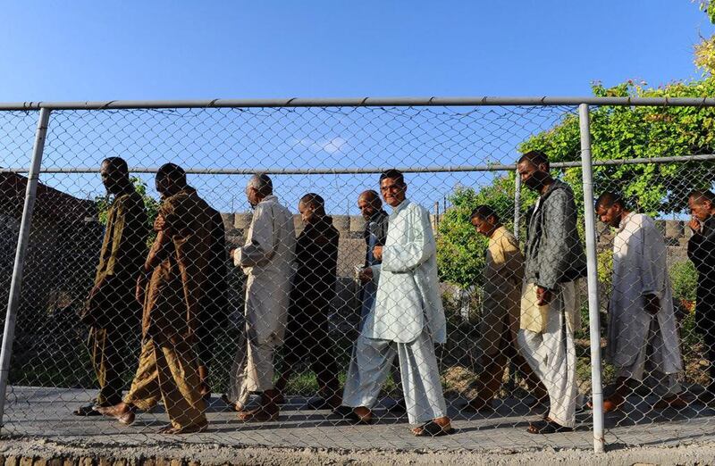 Male residents walk along a fenced pathway outside in the yard.