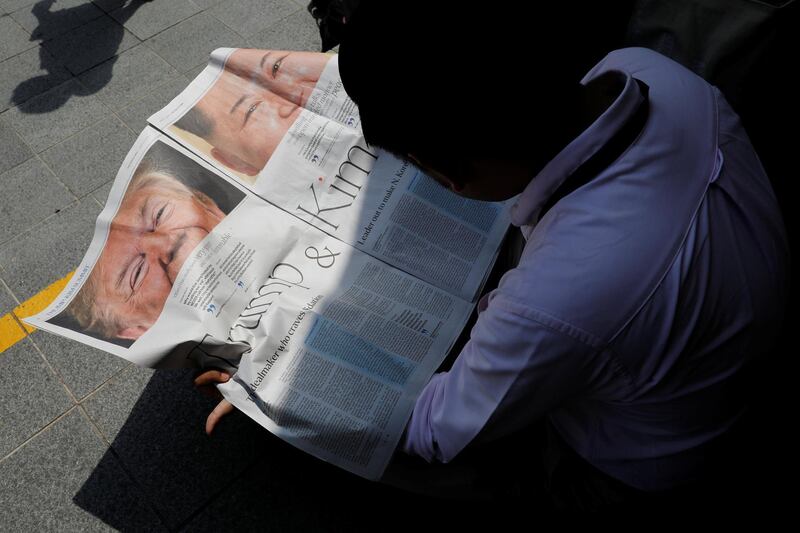 A journalist reads a local newspaper showing an article on the summit between US President Donald Trump and North Korean leader Kim Jong Un near St. Regis hotel in Singapore. Tyrone Siu / Reuters