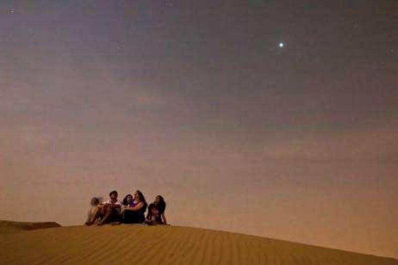 Lehbab - August 13, 2009 - Members of the Punjabi family, foreground L-R Sheila, Munish, Sanjana and Sadhavi along with their friend Parinwaz Navdar (who is sitting behind them) watch the Perseids meteor shower from atop a sand dune near Lehbab (midway between Dubai and Hatta), August 13, 2009. They gathered with other stargazers at an observation gathering sponsored by the Dubai Astronomy Group. (Photo by Jeff Topping/The National)  *** Local Caption ***  JT001-0813-PERSEIDS_MG_8158.jpg