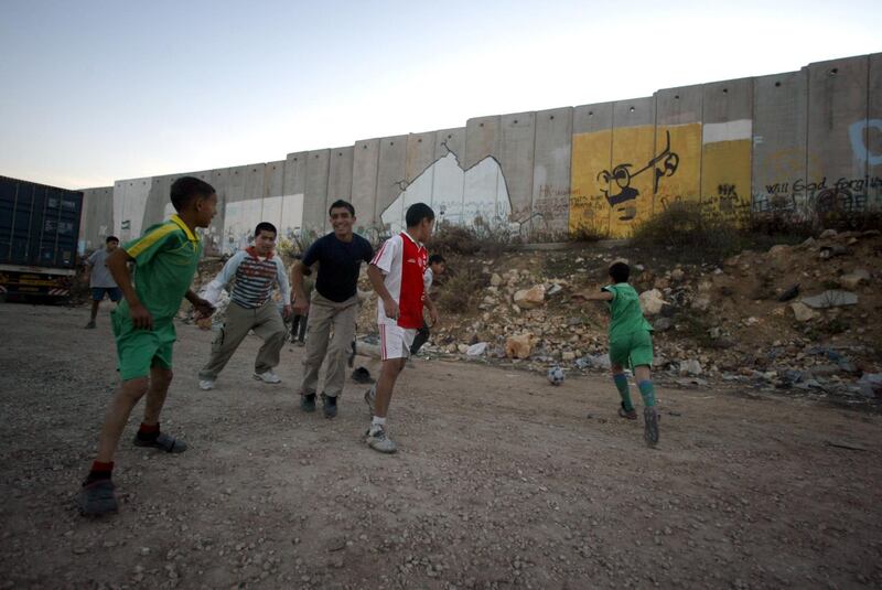 West Bank, Children play football beside the separation wall that separate Jerusalem from west bank in Qalandia refugee camp
Photo by, Jamal Aruri                                                                                      

