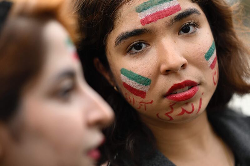A protester has her face painted with an Iranian national flag during a demonstration in support of Kurdish Iranian woman Mahsa Amini during a protest on October 3, 2022 in Nantes, weetern France, following her death in Iran.  - Amini, 22, died in custody on September 16, 2022, three days after her arrest by the notorious morality police in Tehran for allegedly breaching the Islamic republic's strict dress code for women.  in Nantes, western France on September 29, 2022.  (Photo by Damien Meyer  /  AFP)