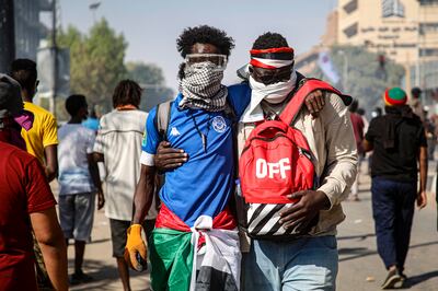 A Sudanese protester helps another affected by tear gas during the clashes with security forces. EPA 