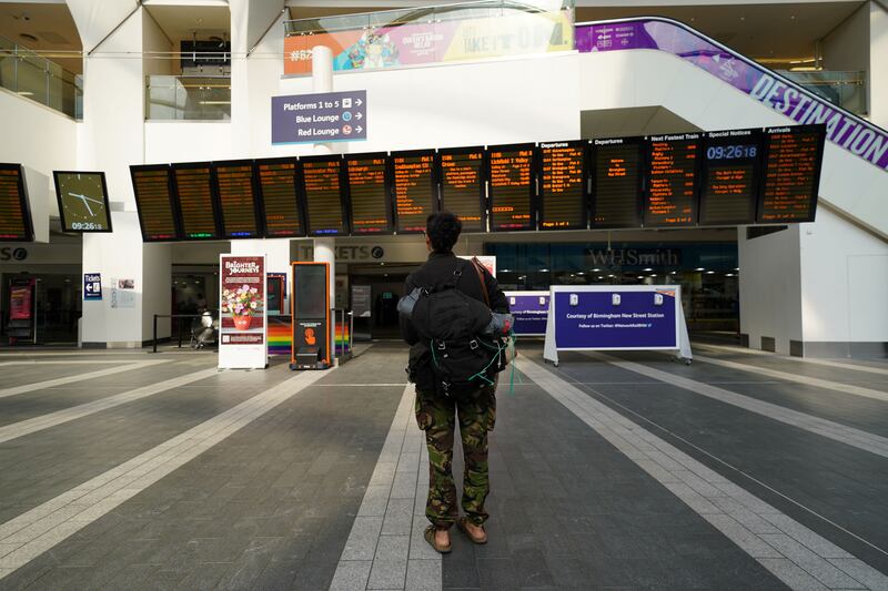 A passenger looks at message boards at Birmingham New Street station. PA