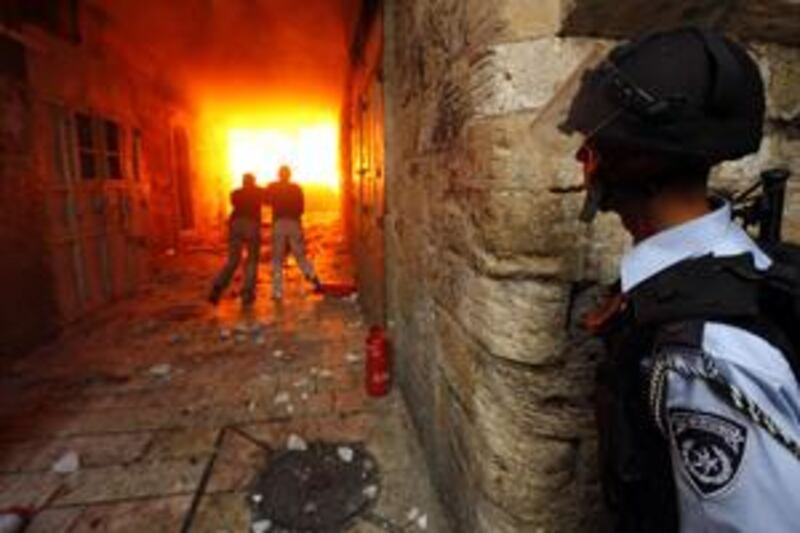 An Israeli police officer watches as Palestinians clear the area after youths threw a petrol bomb during clashes with police in Jerusalem's Old City.