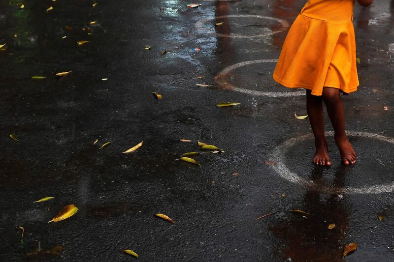 A young girl stands in queue to collect food in the rain in Kolkata.  AFP