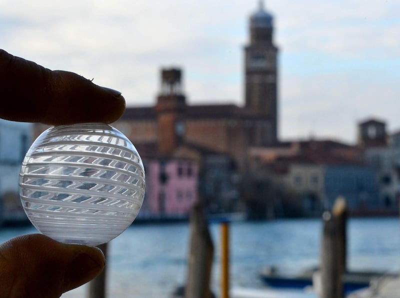 Italian artist and craftsman Davide Penso holds a Murano glass pearl outside his workshop on December 18, 2020. AFP