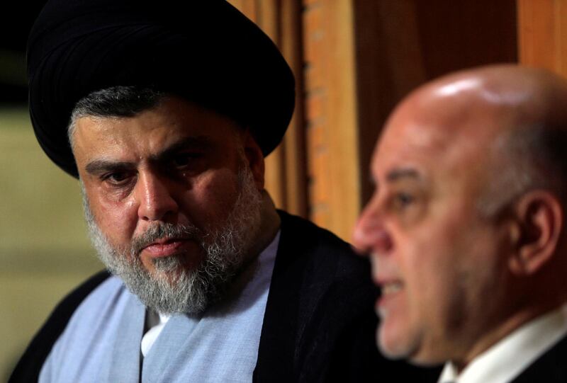 Iraqi Shi'ite cleric Moqtada al-Sadr, who's bloc came first, looks at Iraqi Prime Minister Haider al-Abadi, who's political bloc came third in a May parliamentary election, during a news conference in Najaf, Iraq June 23, 2018. REUTERS/Alaa al-Marjani
