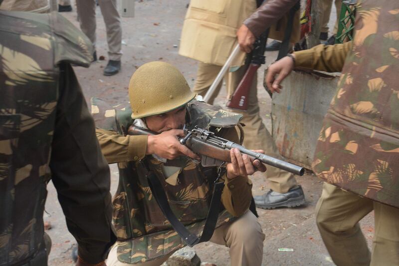 A police personnel aims his gun towards protesters during demonstrations against India's new citizenship law in Meerut.  AFP