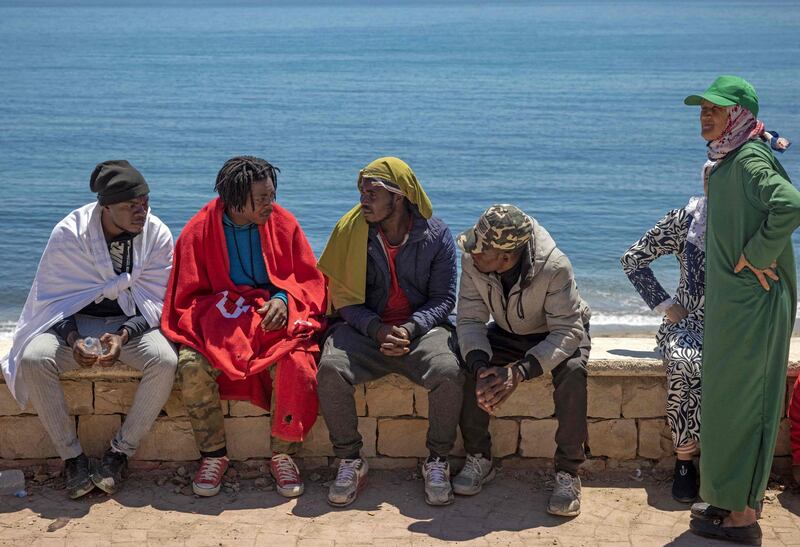 Migrants sit on a sea wall in the northern town of Fnideq, Morocco, as they prepare to attempt to cross the border into Spain's North African enclave of Ceuta. AFP