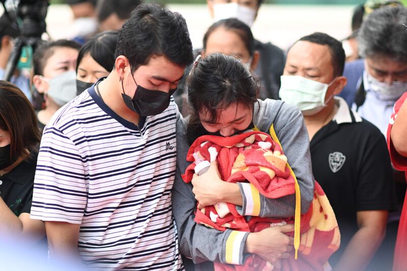 Sittipong Taothawong, left, comforts his wife Kanjana Buakumchan as she holds their child's milk bottle and blanket while standing outside the nursery. AFP