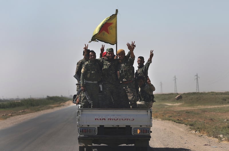 U.S.-backed Syrian Democratic Forces fighters stand on their pickup as the flash victory signs on a road that links to Raqqa city where they battle against the Islamic State militants, northeast Syria, Wednesday, July 26, 2017. (AP Photo/Hussein Malla)