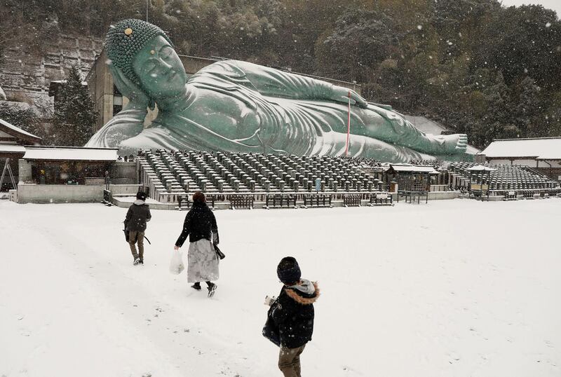 People walk on the snow-covered Nanzoin buddhist temple towards the bronze statue of reclining Buddha in Sasaguri town.  AFP