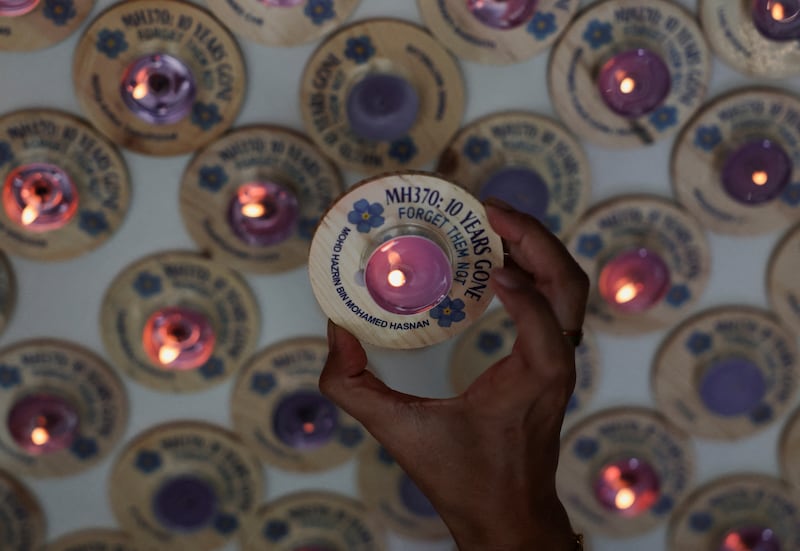 A family member of missing cabin crew member Mohd Hazrin Mohamed Hasnan holds a candle bearing his name during a remembrance event marking the 10th anniversary of the flight's disappearance, in Subang Jaya, Malaysia on March 3. Reuters